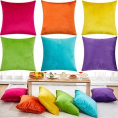 four different colored pillows sitting on top of a white floor next to a coffee table