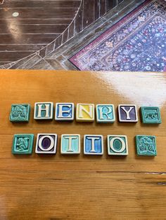 the word happy holidays spelled out in small blocks on a wooden table next to a rug