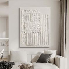 a living room filled with furniture and a white painting hanging on the wall above it