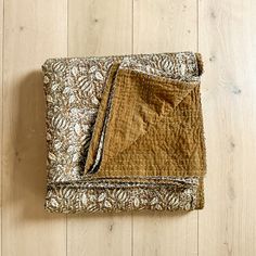 a brown and white blanket sitting on top of a wooden floor