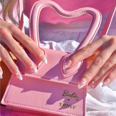 a woman's hand holding a pink purse with white nail polishes on it