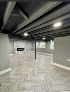 an empty room with gray walls and wood flooring in the center is lit by recessed lights