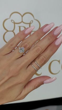 a woman's hand with pink manicured nails and two engagement rings on it