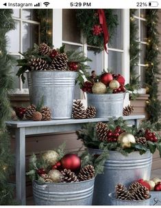 three metal buckets filled with christmas decorations