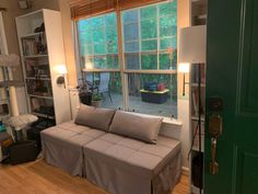 a couch sitting in front of a window next to a green door