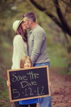 a man and woman holding a sign that says save the date