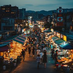 an outdoor market with many people walking around it at night, in the middle of town