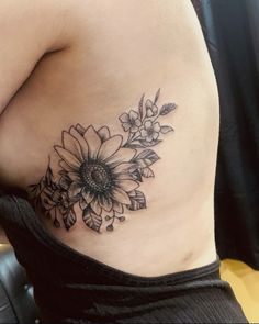 a sunflower tattoo on the side of a woman's stomach