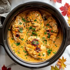 a crock pot filled with chicken covered in gravy and garnished with parsley