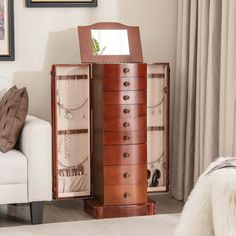 a white couch sitting next to a tall wooden cabinet filled with jewelry and other items