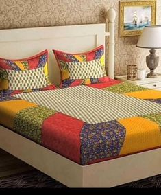 a bed with colorful quilts and pillows on top of it next to a night stand