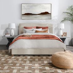 a bedroom with a bed, rugs and paintings on the wall above it in neutral colors