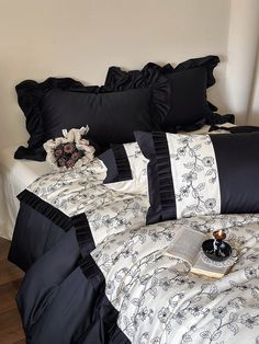 a bed with black and white comforters, pillows and an open book