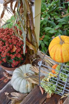 pumpkins and gourds are sitting on the porch