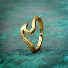 a gold ring that is shaped like a heart on a green surface with the word love written