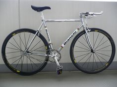 a silver bicycle parked in front of a gray wall with yellow and white lettering on it