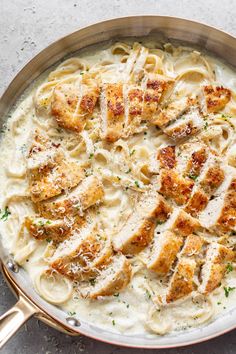 a pan filled with chicken alfredo sauce and parmesan cheese on the side,