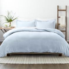 a bed with light blue sheets and pillows