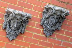 two stone sculptures on the side of a brick wall