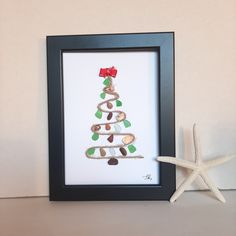 a christmas tree made out of sand and seashells is displayed in front of a starfish