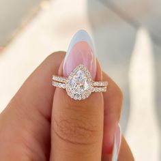 a woman's hand holding a diamond ring with two diamonds on top of it