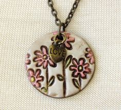 a necklace with flowers and a heart hanging from it's center on a chain