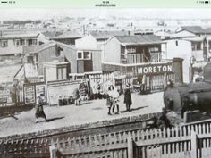 an old black and white photo of people on a train track in front of houses