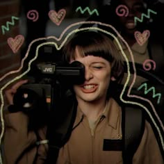 a woman holding a camera in front of her face with hearts drawn on the background