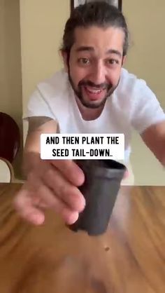 a man holding a cup with the words and then plant the seed down on it