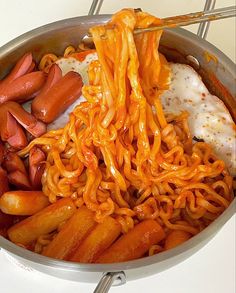 noodles and carrots are being cooked in a pan