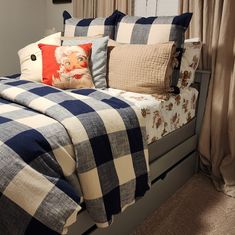 a bed with blue and white checkered comforter on top of it next to a window