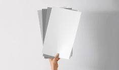 a person holding up three white papers in the air