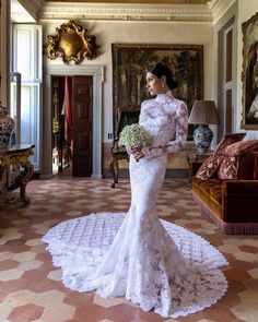 a woman in a white wedding dress holding a flower bouquet and looking off into the distance