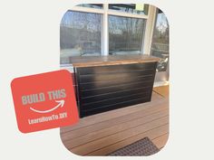 a black cabinet sitting on top of a wooden floor in front of a large window