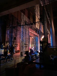 people sitting at tables in front of a building with scaffolding on the walls