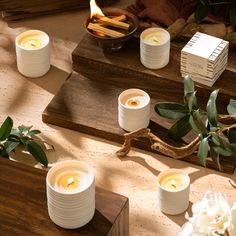 candles are sitting on the table next to some flowers and other things in front of them