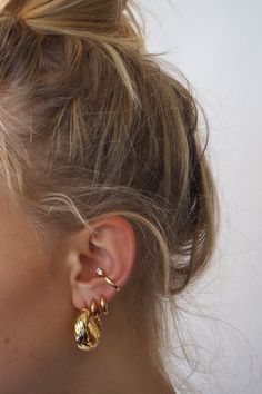 a close up of a person wearing some kind of gold earring on their left ear