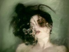 a blurry image of a woman's face with her hair blowing in the wind