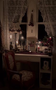 a chair sitting in front of a window next to a desk with candles on it