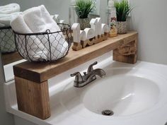 a white sink sitting under a bathroom mirror next to a wooden shelf filled with towels