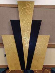 a gold and black sculpture sitting on top of a carpeted floor next to a wall