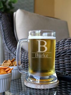 a beer mug sitting on top of a table next to a bowl of crackers