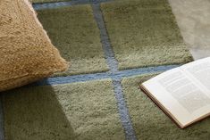 an open book laying on the floor next to a pillow