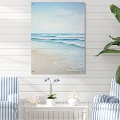 a living room with two blue chairs and a painting on the wall above it that has waves coming in from the ocean