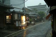 an empty street in the rain with shops on both sides and umbrellas hanging from buildings