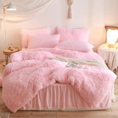 a bed covered in pink fluffy blankets and pillows