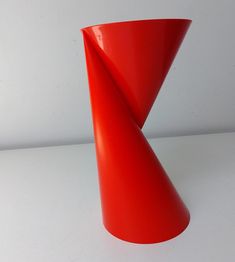 a red vase sitting on top of a white table