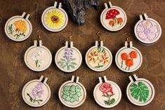 nine embroidered flower designs are shown on small round hoop earrings with gold earwires