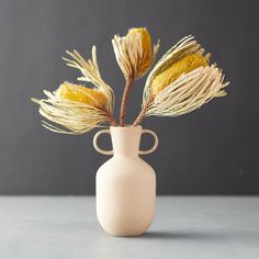 a white vase with some yellow flowers in it