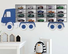 a room with a toy truck and cars on the wall next to a white chair